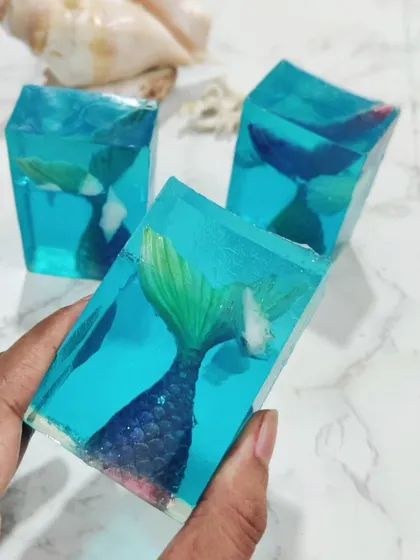 A trio of my mermaid tail soaps. The embeds are painted with shimmering mica to make them look magical, as if they are swimming in the clear blue water.