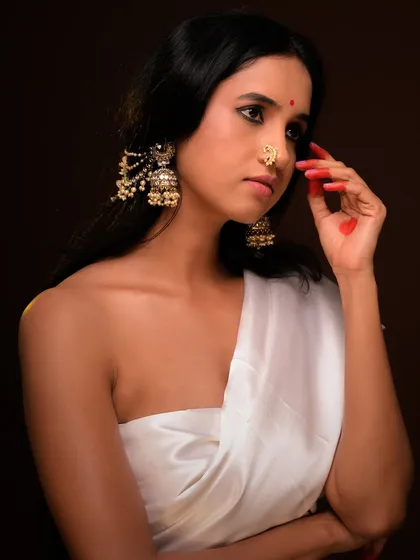 A contemplative pose that highlights the jewelry and the traditional bindi. The dark background makes the subject stand out beautifully.
