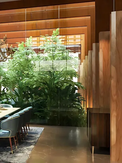 Bringing nature indoors is a key part of our design philosophy. In this dining space, a glass wall reveals an internal courtyard filled with lush greenery, creating a sense of tranquility and a powerful connection to the natural world.