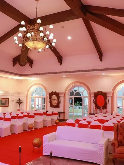 This indoor banquet hall at Madh is arranged for a reception or sangeet. The seating is organized with classic white and red chair covers, creating a formal yet festive environment for guests to enjoy the event.