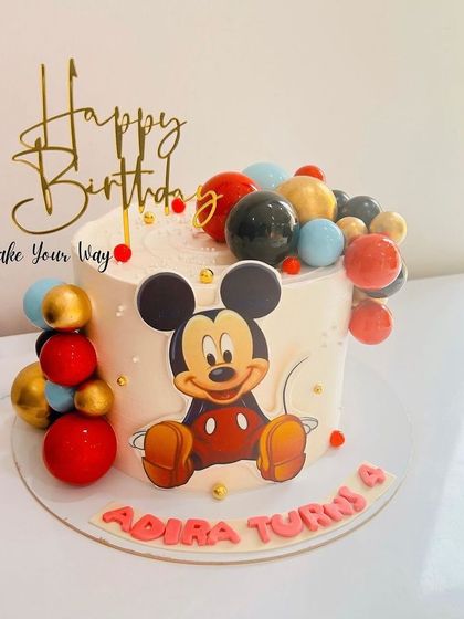 A classic Mickey Mouse cake decorated with a cascade of colorful chocolate spheres for a modern touch.