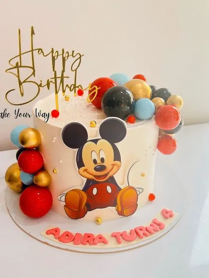 A classic Mickey Mouse cake decorated with a cascade of colorful chocolate spheres for a modern touch.