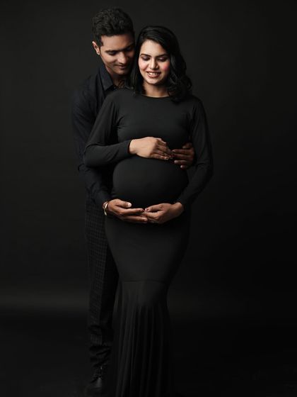 A classic maternity pose where the partner lovingly embraces the mom-to-be from behind, both cradling the bump. It’s a beautiful symbol of partnership.