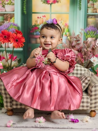 The smallest flower with the biggest smile, this baby girl is surrounded by a beautiful floral shop setup.