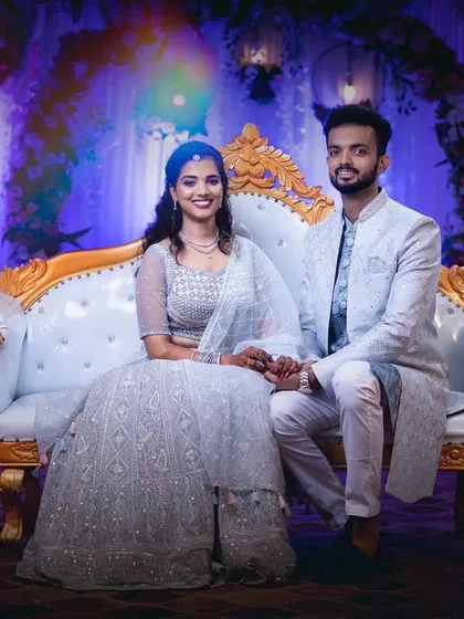 A formal portrait of the couple seated on an elegant white sofa during their engagement ceremony.