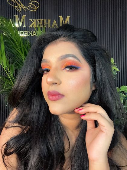 A full view of the colorful eye makeup look. The vibrant orange and blue eyeshadow is paired with a soft pink lip to balance the look.