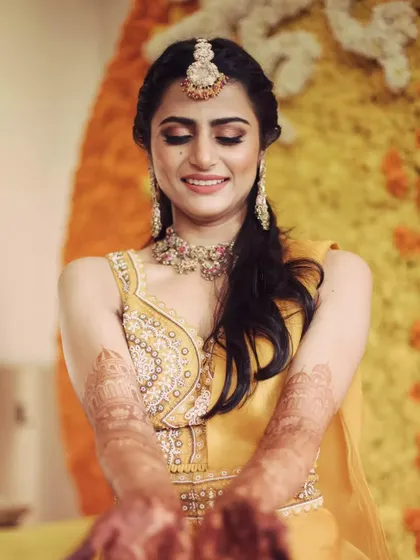 A beautiful portrait of the bride showing off her intricate henna design, with the warm yellow decor creating a perfect glow.