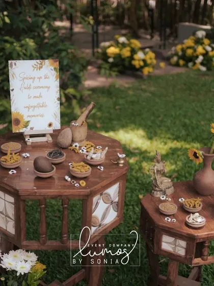 A wider view of the Haldi station, with rustic wooden tables and sunflower arrangements in a garden setting.