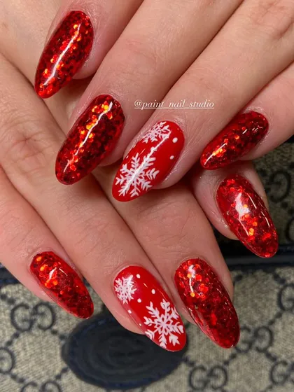 Getting into the holiday spirit with these festive red glitter nails. The deep red glitter is paired with accent nails featuring hand-painted white snowflakes for a perfect Christmas look.
