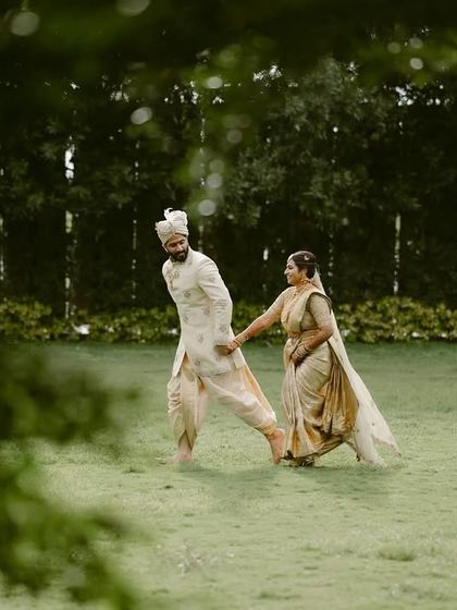 A quiet moment in the rain. The couple walks together on the wet grass, creating a serene and romantic scene.