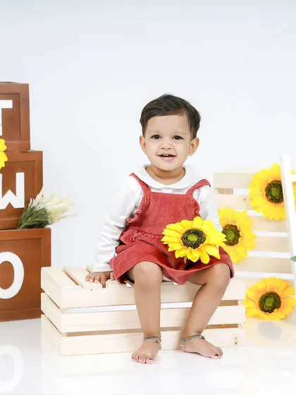 Holding a sunflower, this little girl is the star of her second birthday shoot. Her happy expression is simply priceless.