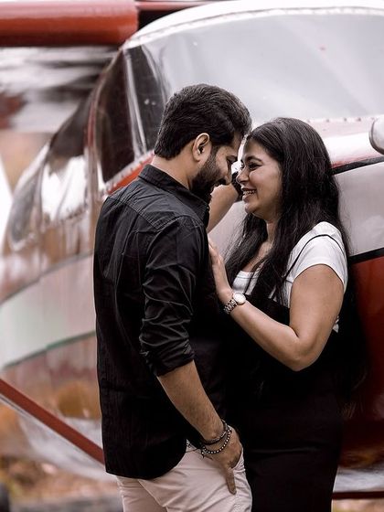 An intimate and happy moment shared by a couple, leaning against a small airplane prop.