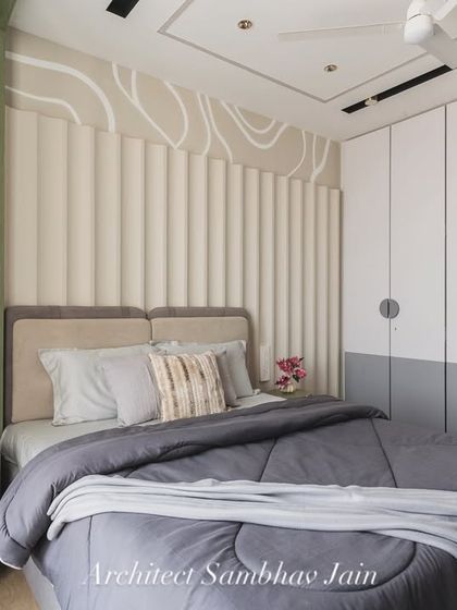 This bedroom is a quiet conversation between textures and tones. A calming palette of sage green, soft greys, and warm beige forms the base, while the fluted headboard and fluid wall pattern add depth and dynamism.