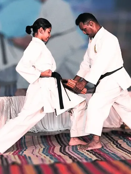 As a master, I personally guide my students to perfect their power. Here, I assist a female black belt in focusing her energy for a successful knee strike, a vital technique in close-quarters self-defense.