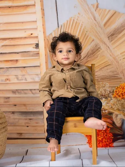 Taking a seat in his rustic-themed set. This is a great setup for capturing a one-year-old's milestone portraits.