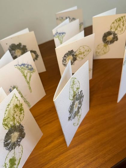 An array of my handcrafted greeting cards, each standing open to display its unique floral design. These are available for individual purchase or in bulk for special orders.