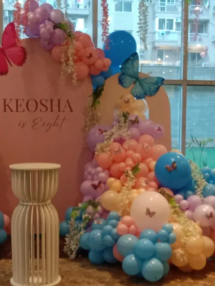 A beautiful butterfly theme for an eighth birthday. The pastel pink backdrop is adorned with a cascade of colorful balloons and delicate butterfly cutouts, creating a whimsical photo corner.