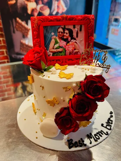 A heartfelt birthday cake for the "Best Mom Ever," featuring a cherished photo in a red fondant frame and decorated with fresh roses.