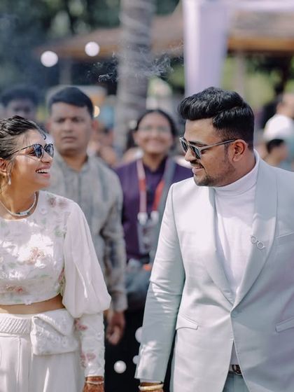 The couple makes a grand entrance at their carnival-themed party, surrounded by performers. Their expressions show their excitement and joy.