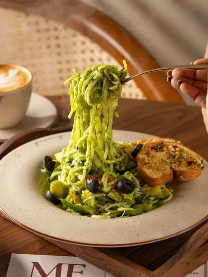 A pesto spaghetti pasta pull, a great action shot to make the dish look extra cheesy and delicious.