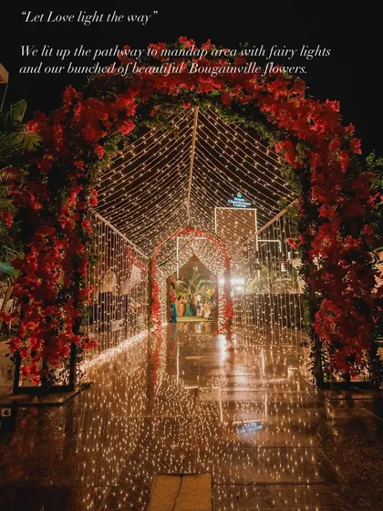 A stunning fairy light tunnel decorated with red bougainvillea, creating a magical pathway to the mandap area. This enchanting entrance set a romantic tone for the evening wedding ceremony.