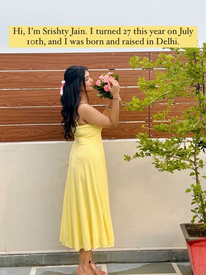 A little introduction: I'm Srishty Jain, a Delhi-born-and-raised girl who turned 27 this year. This picture shows me in a sunny yellow maxi dress, smelling pink flowers.