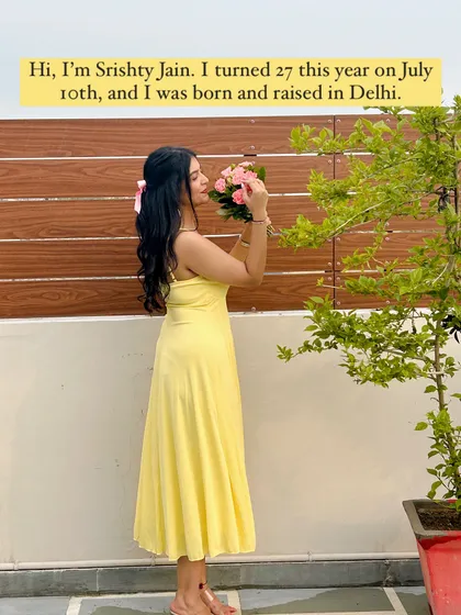 A little introduction: I'm Srishty Jain, a Delhi-born-and-raised girl who turned 27 this year. This picture shows me in a sunny yellow maxi dress, smelling pink flowers.