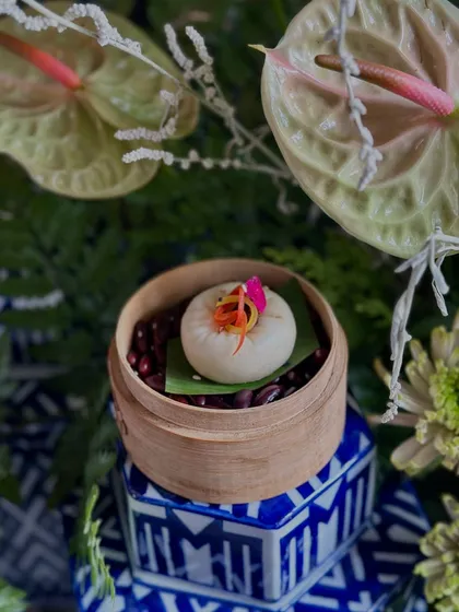 A Shanghai Vegetable Bao Bun, filled with flavourful vegetables and roasted chilli oil, served in a mini bamboo steamer for an authentic touch.