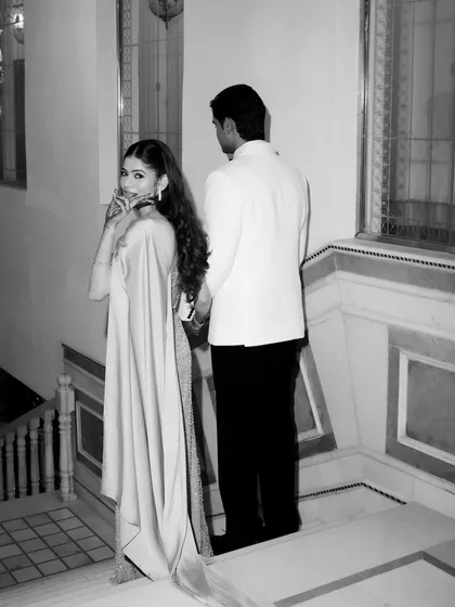 A classic "look back" shot captured in elegant monochrome. As the couple ascends the stairs, the bride's glance back at the camera is full of grace and charm.
