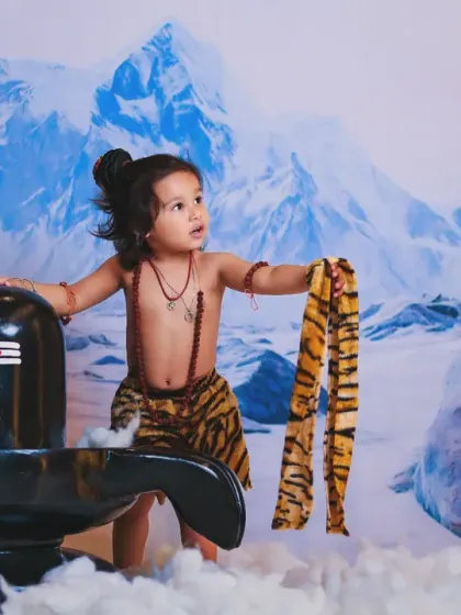 A powerful portrait of a little boy dressed as Mahadev, set against a backdrop of the snowy Himalayas.