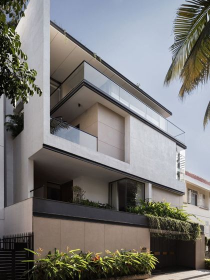 The facade of Villa Aish in Bengaluru, built on a compact 200 sqm urban plot. The design balances the need for privacy with a desire for openness through a series of stacked volumes, recessed balconies, and integrated planters, creating a home that is both intimate and connected to its surroundings.