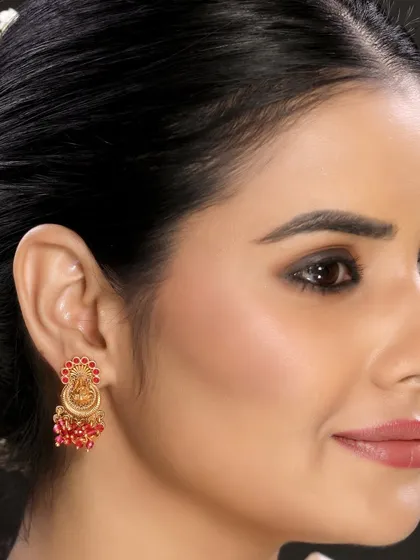 This image focuses on a model wearing traditional temple earrings with red beadwork. The side profile and hair styling draw attention directly to the earring, making it ideal for e-commerce listings.