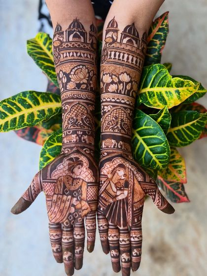 This design from the Bridal Extravaganza package features detailed bride and groom portraits on the palms, surrounded by intricate patterns and auspicious elephants on the forearms.