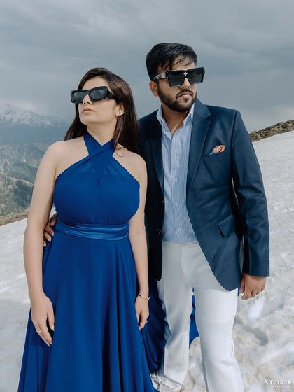 A stylish, high-fashion pose of the couple in sunglasses against the snow.