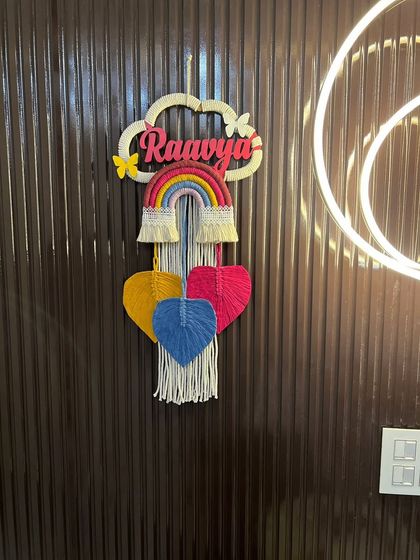 This 'Raavya' nameplate is a perfect example of my classic rainbow and cloud design. It features colorful hanging hearts and delicate butterfly accents for an extra touch of whimsy.