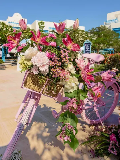 A whimsical pink bicycle with a basket overflowing with flowers, serving as a charming and picturesque decor element for the Victorian-themed luncheon.