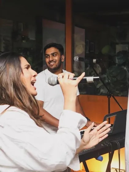Shanelle and Aryaman singing together while Brendan smiles from the keyboards. These candid moments capture the joy we feel when we perform.