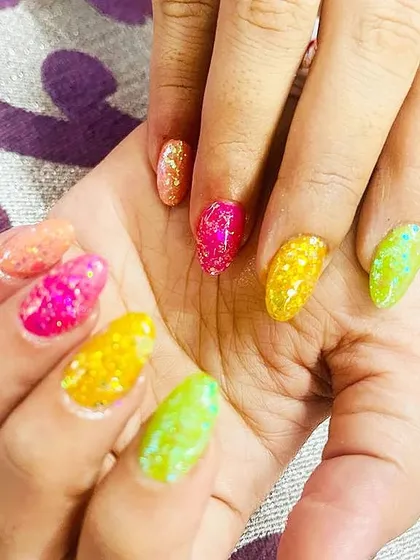 A fun and vibrant "jelly" nail look with multi-colored, translucent polishes packed with glitter.