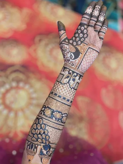 A stunning shot of a full-arm bridal mehendi. The design is filled with multiple peacock motifs, creating a sense of movement and grace.