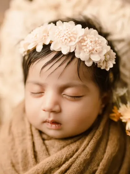 A close-up portrait highlighting the baby's peaceful expression and delicate floral headband.