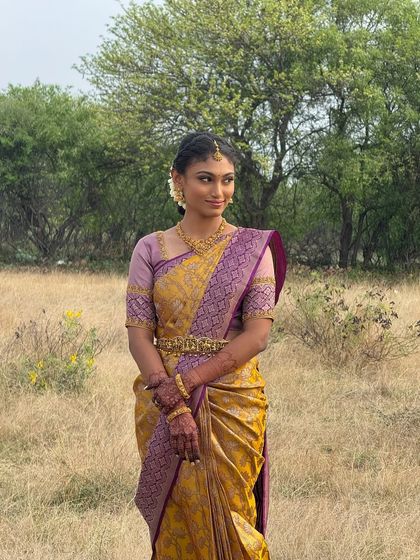 A poised shot of Priyanka, showing her full engagement look. The yellow and purple saree is a beautiful choice that complements her skin tone and the natural makeup.