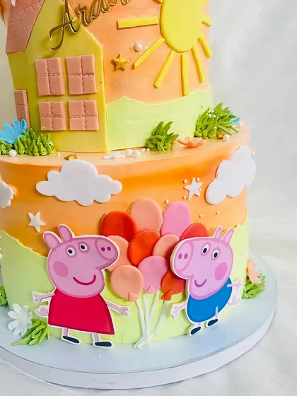 A detailed shot of Peppa and George holding balloons on the two-tier cake.