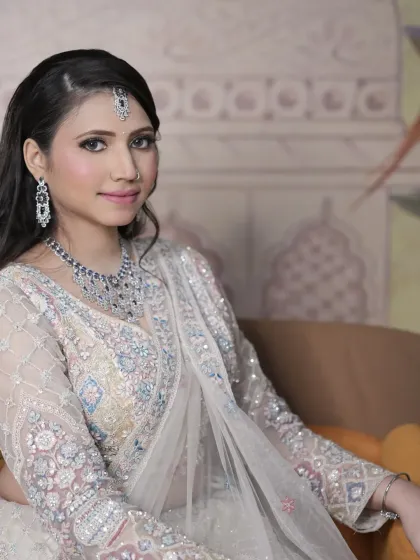 A close-up portrait of the client, showing the delicate jewellery paired with the ivory lehenga.
