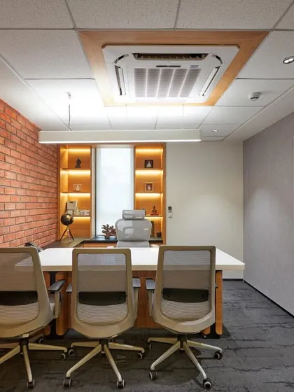 A manager's cabin with an exposed brick accent wall, a large whiteboard for strategy sessions, and built-in shelving with accent lighting. The design is both practical and stylish.