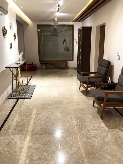 The entrance area of our Hyderabad project, featuring a custom console table with a geometric gold base. The space is lit with architectural track lights that highlight the artwork and create a warm ambiance.
