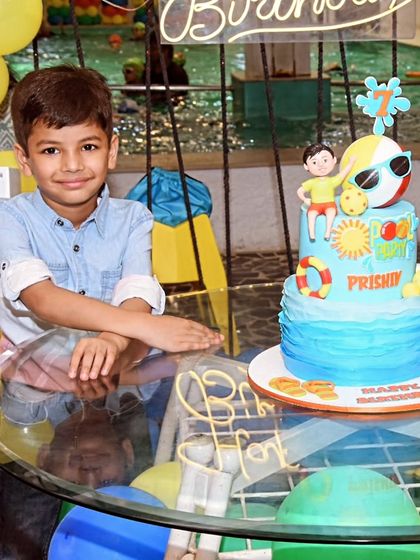 The birthday boy posing proudly with his summer-themed cake, complete with edible waves and flip-flops.