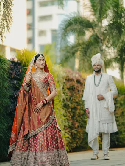 A beautiful portrait of the bride with the groom approaching in the background, capturing the 'first look' moment before the ceremony begins.