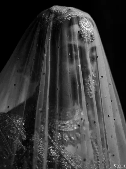 An artistic black and white portrait of the bride, Aashi, her face veiled, creating a timeless and ethereal look.