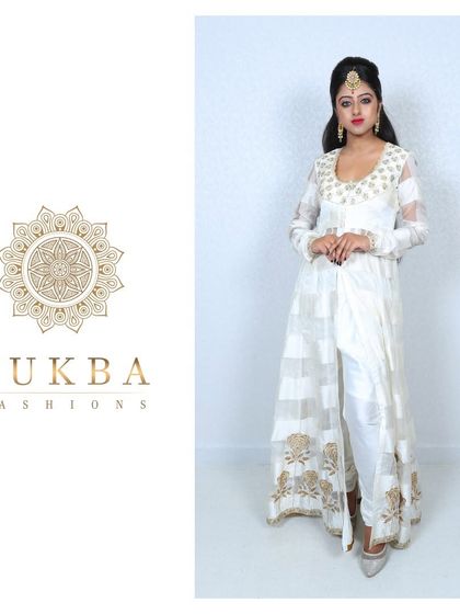 A model in a white, front-slit Anarkali gown. The sheer fabric is embellished with gold block prints, creating a look that is both ethereal and modern.