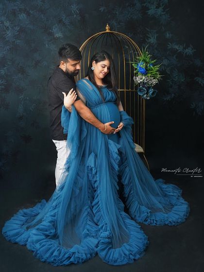 A romantic portrait of the couple by the birdcage. The deep blue gown and the partner's embrace create a moody and elegant scene.